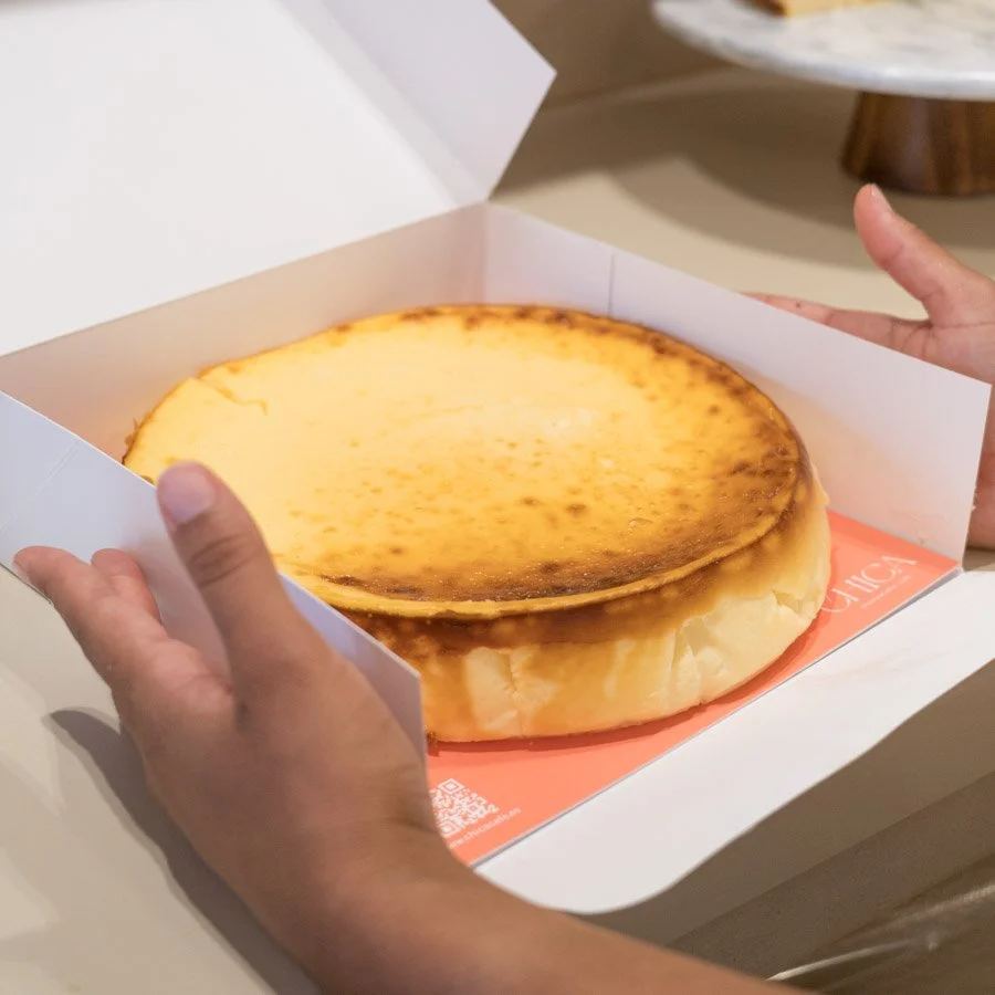 Unas manos abriendo la caja blanca de CHICA con una cheesecake dentro