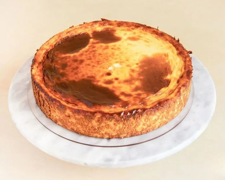 Cheesecake No tan clásica sencer, amb la superfície daurada i taques de caramel