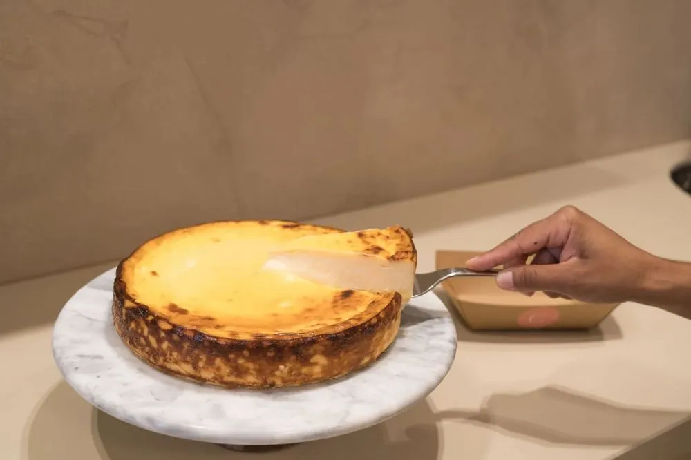 Cortando una cheesecake recién horneada en el mostrador de la tienda