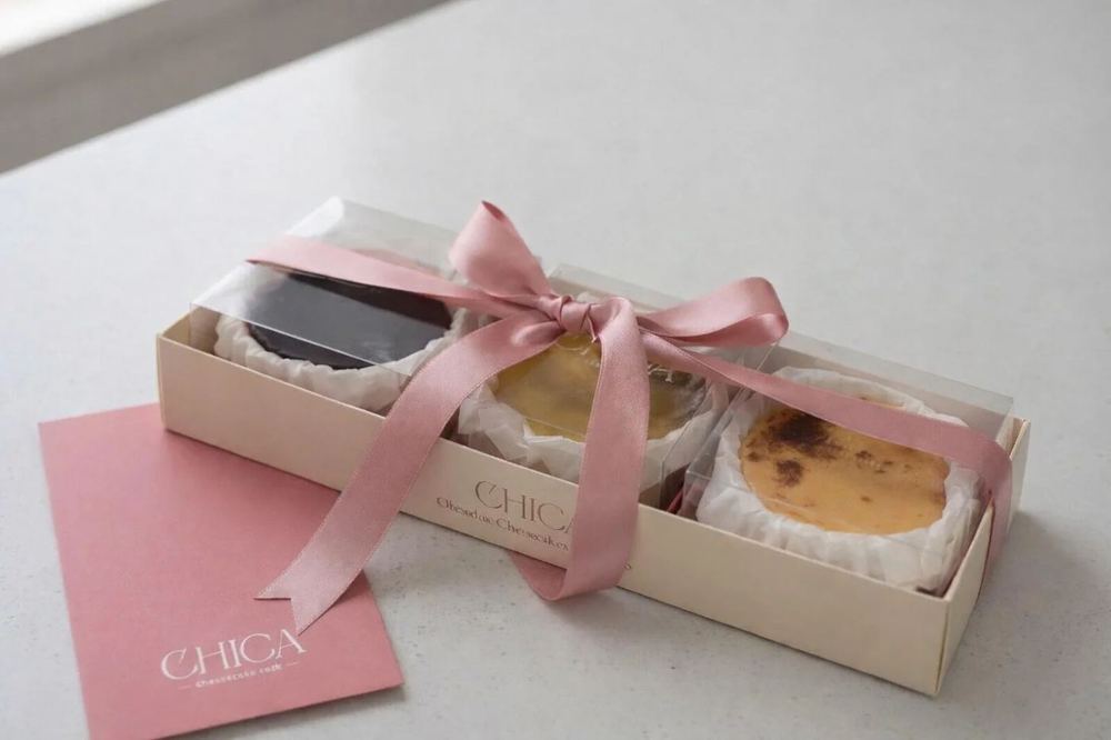 Caja con las tres cheesecakes pequeñas atada con un lazo rosa