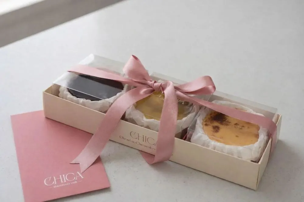 Caixa amb els tres cheesecakes petits lligada amb un llaç rosa